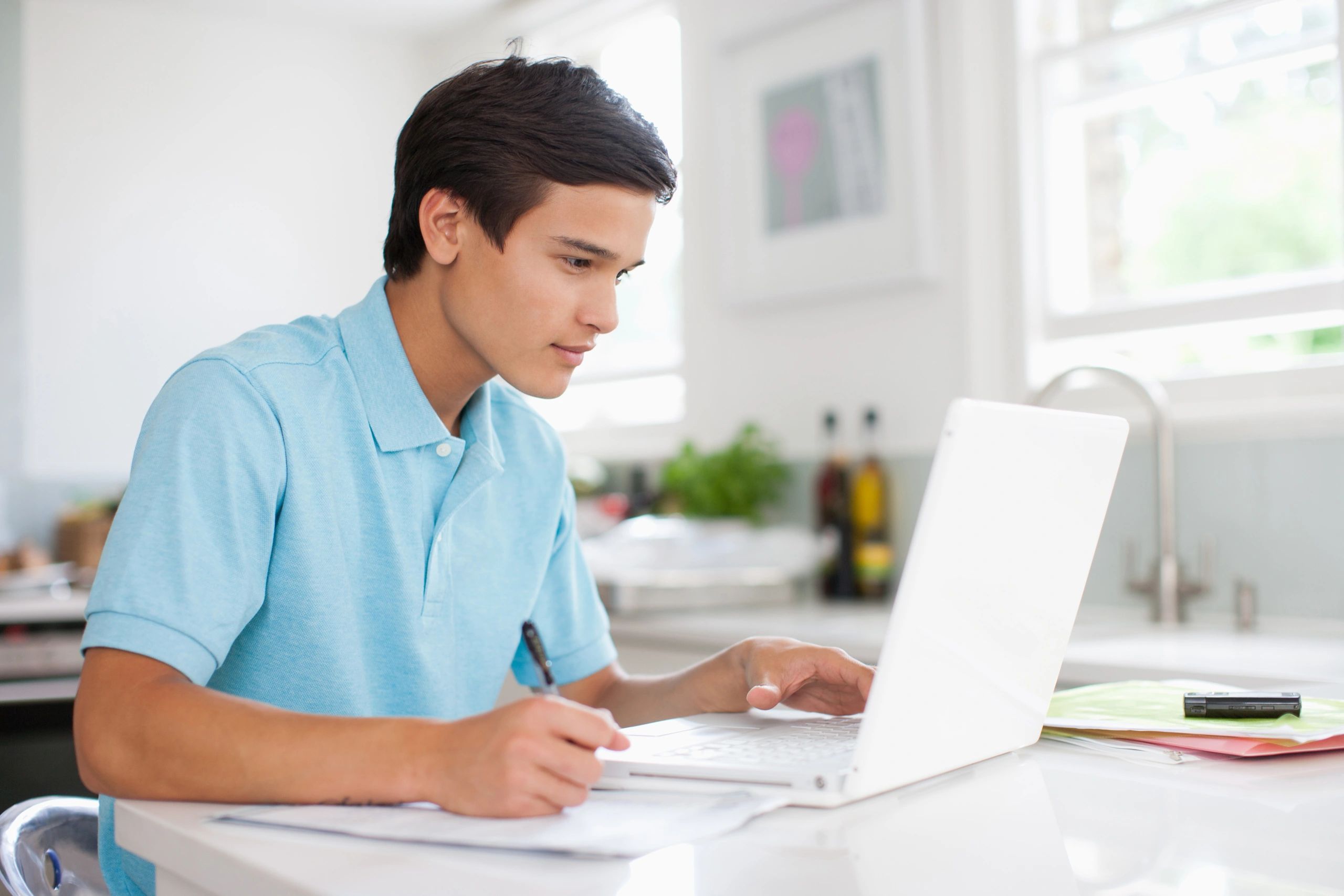 Teenage boy studying with a laptop