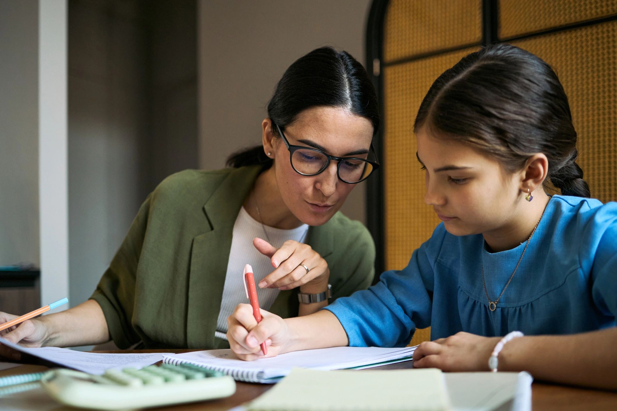 Tutor guiding a teenage student during a math lesson